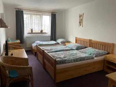 a bedroom with two beds and a table and a desk at Pension Hájek in Prague