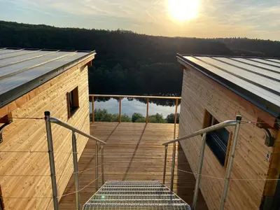 a building with a deck with the sun in the background at Chatka - B - Vyhlídka nad řekou in Zdiby