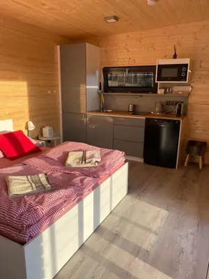 a bedroom with a large bed and a kitchen at Chatka - B - Vyhlídka nad řekou in Zdiby