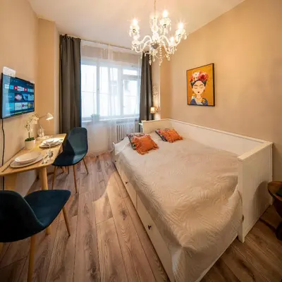 a bedroom with a bed and a desk and a chandelier at Studio Apartment - Tower Petrin in Prague