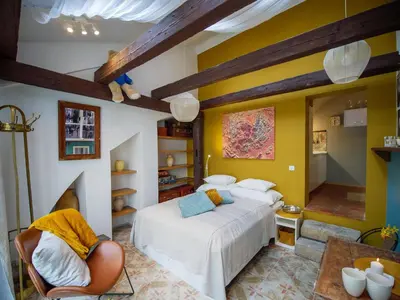 a bedroom with yellow walls and a bed and a chair at Romantic nest under Prague Castle in Prague