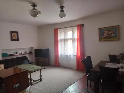 a living room with a table and a window with red curtains at Apartmán Měňany in Měňany