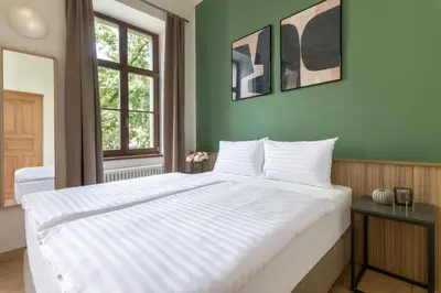 a large white bed in a room with green walls at Bohemian Dreams Apartments and Suites by Dwellfort in Prague