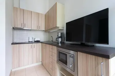 a kitchen with wooden cabinets and a flat screen tv at Bohemian Dreams Apartments and Suites by Dwellfort in Prague