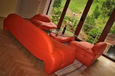 an orange couch and two chairs in a room with a window at Vila Prag in Prague