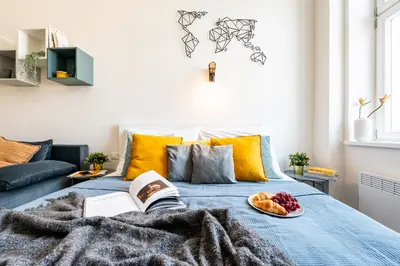 a bed with a book and a plate of fruit on it at Prague Days - Stylish Condo with Netflix in Hip Karlín in Prague