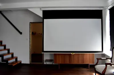 a large screen in a living room with stairs at Lux Duplex rooftop loft with an amazing terrace & home cinema in Prague