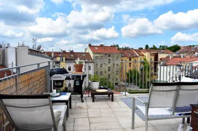 a balcony with chairs and a view of a city at Lux Duplex rooftop loft with an amazing terrace & home cinema in Prague