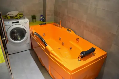 an orange bath tub next to a washing machine at NEW CENTRAL ROOFTOP with private WELLNESS, Sauna & Whirlpool bath in Prague