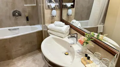 a bathroom with a sink and a mirror and a tub at FLEUR DE LIS HOTEL in Prague