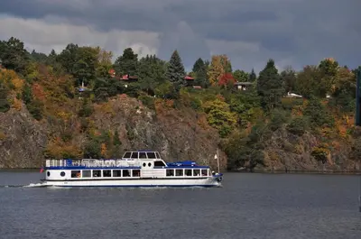 a white boat on the water near a mountain at Hotel VZ Měřín in Merin