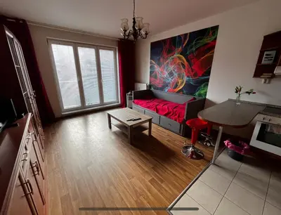 a living room with a red couch and a painting on the wall at MONFas APARTMENT GARDEN CITY in Prague