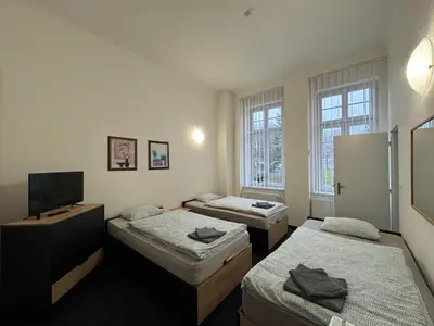 a room with three beds and a flat screen tv at Penzion Zahrada Čech in Litoměřice