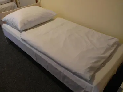 a bed with white sheets and a pillow on it at Hotel Harfa in Prague