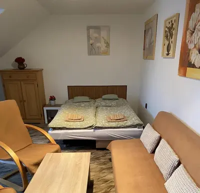 a bedroom with a bed and two chairs at Apartmán Na Ostrově Beroun in Beroun