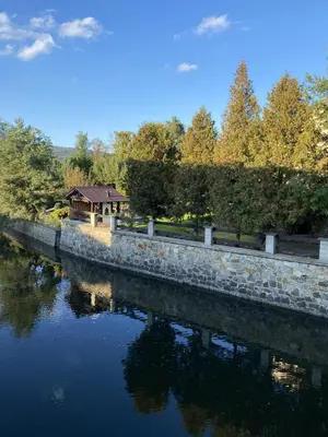 a stone wall next to a river with a gazebo at Apartmán Na Ostrově Beroun in Beroun