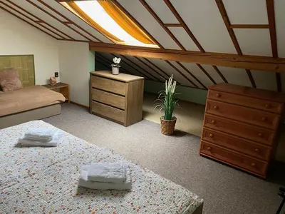 a attic room with two beds and a dresser and a bedroom at Apartmán Na Ostrově Beroun in Beroun