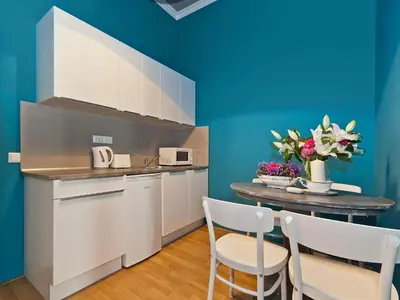 a kitchen with white cabinets and a table with chairs at Royal Prague City Apartments in Prague