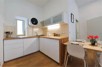 a kitchen with white cabinets and a table and chairs at Pat & Mat Apartment in Prague
