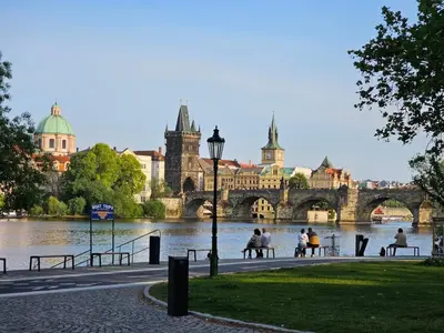 a group of people sitting on benches next to a river at LYLY APARTMENT - Modern apartment with free parking in Prague