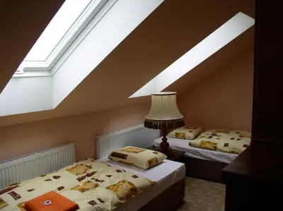 two beds in a room with a sloping ceiling at Penzion Rozkoš in Pruhonice