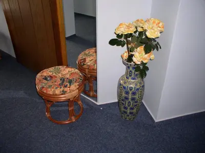 a blue and white vase with yellow flowers and a stool at Penzion Rozkoš in Pruhonice