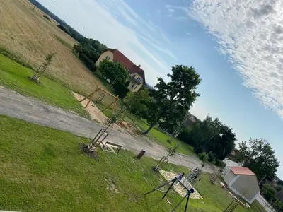 a field with a house on the side of a hill at Penzion Rozkoš in Pruhonice