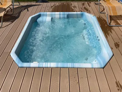 a blue hot tub on a deck with a chair at Penzion Rozkoš in Pruhonice