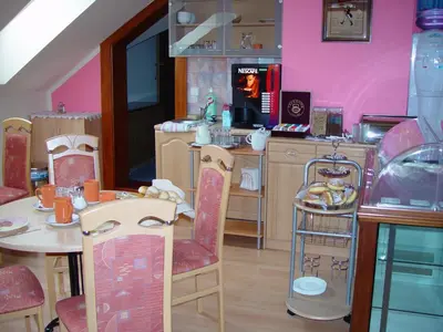 a dining room with a table and a kitchen with pink walls at Penzion Rozkoš in Pruhonice
