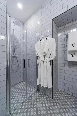 a bathroom with a shower with white robes at The Viaduct - Suites & More in Prague