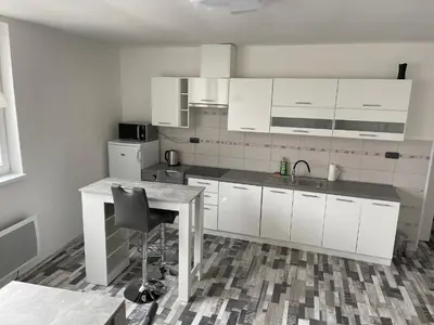 a kitchen with white cabinets and a table with a chair at Apartmány Piller in Roudnice nad Labem