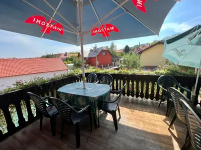 a table with chairs and an umbrella on a deck at Restaurace a penzion Na Růžku in Mořina