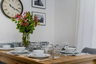 a table with plates and glasses and a clock on the wall at Florenc Apartments Prague 1 by Michal&Friends in Prague