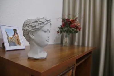 a statue of a bust on a wooden table with a vase of flowers at Heart of Old Town Apartment by National Theater in Prague