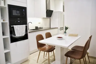 a white kitchen with a white table and chairs at Heart of Old Town Apartment by National Theater in Prague