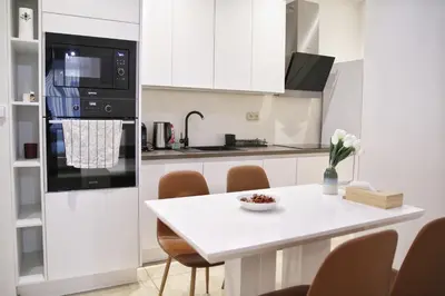 a white kitchen with a white table and chairs at Heart of Old Town Apartment by National Theater in Prague