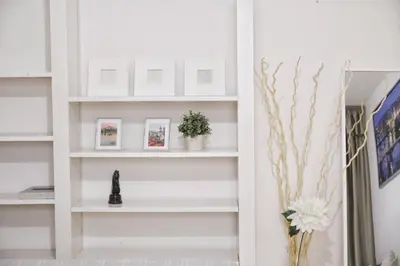 a room with white shelves with pictures and flowers at Heart of Old Town Apartment by National Theater in Prague