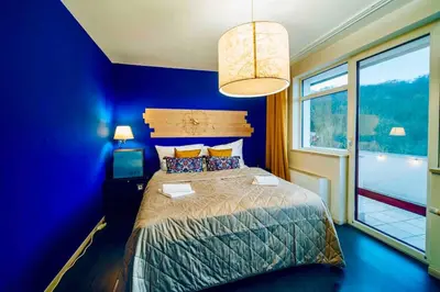 a blue bedroom with a bed and a window at Lovely 3BD - Rooftop - Jacuzzi&Sauna in Prague