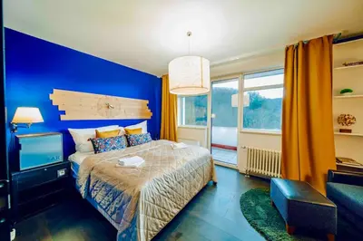 a blue bedroom with a bed and a large window at Lovely 3BD - Rooftop - Jacuzzi&Sauna in Prague