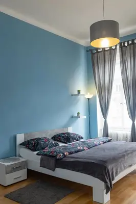 a blue bedroom with a bed and a blue wall at I.P.Pavlova in Prague