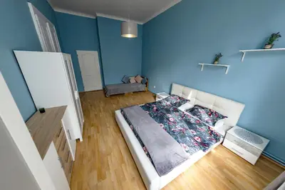 a bedroom with a bed with blue walls and wooden floors at I.P.Pavlova in Prague