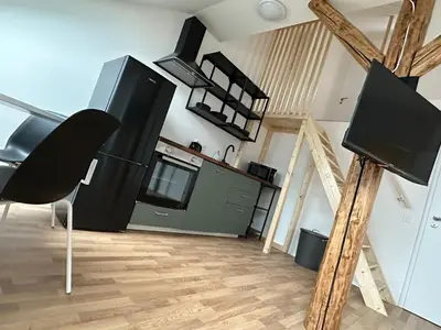 a living room with a tv and a kitchen at Žižkov tower suites in Prague