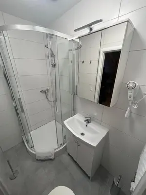 a white bathroom with a shower and a sink at Žižkov tower suites in Prague