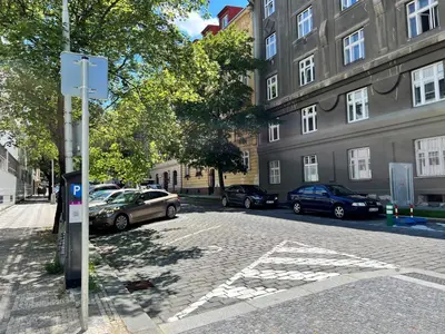 a street with cars parked in front of a building at PRAGUE’s HIDDEN PEARL in Prague