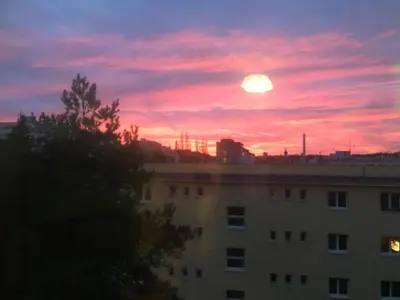 a sunset over a building with the sun in the sky at Kiki & Luky family apartment by Prague Castle in Prague