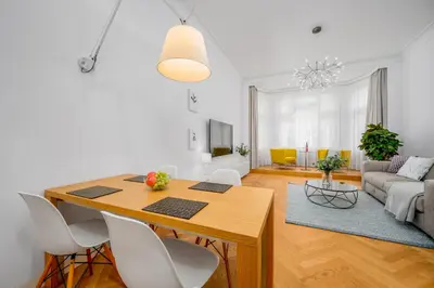 a living room with a wooden table and white chairs at Prague Days - City Central One-bedroom Apartment right next to Old Town Square in Prague
