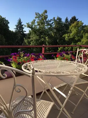a white table and chairs on a balcony with flowers at Apartmá v srdci Poděbrad in Poděbrady