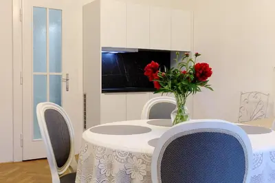 a table with a vase of red flowers on it at Apartmá v srdci Poděbrad in Poděbrady