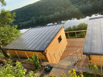 a wooden house with a solar roof and a deck at Chatka - A - Vyhlídka nad řekou in Zdiby