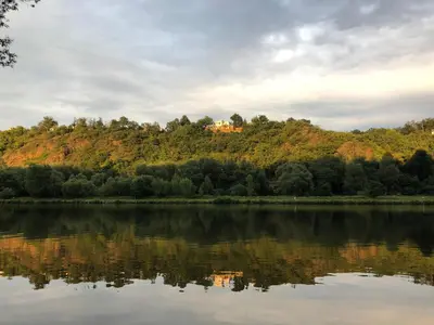 a house on top of a hill next to a lake at Chatka - A - Vyhlídka nad řekou in Zdiby